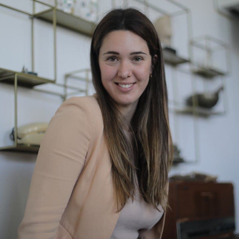 Retrat de la Marta Martí, arquitecta, somrient en un interior amb prestatgeries